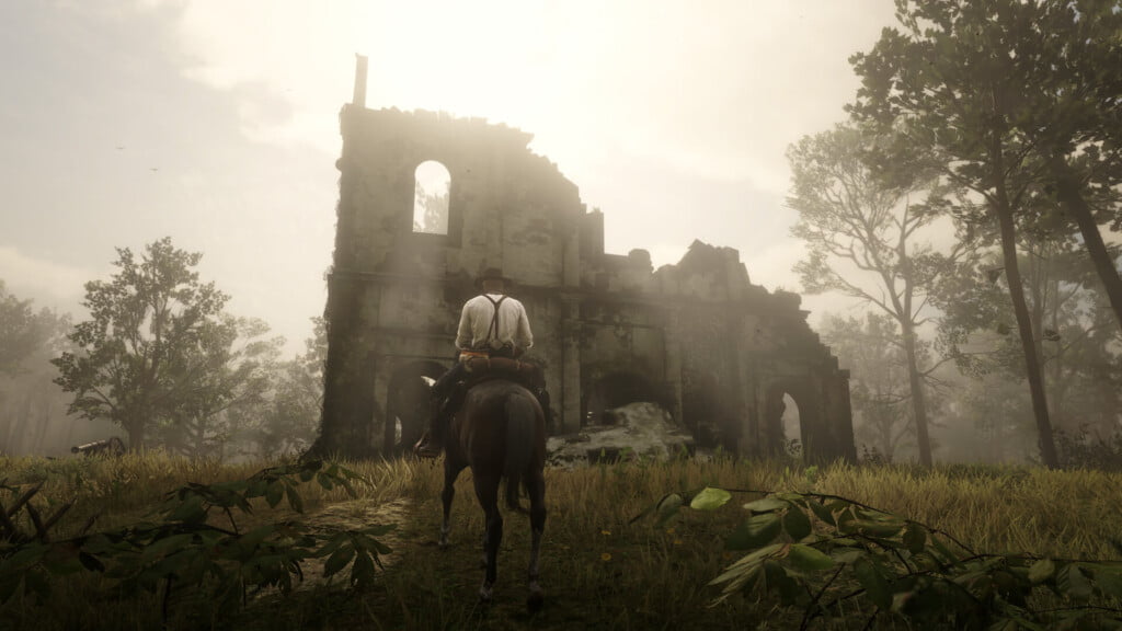 Arthur Morgan on a bay Turkoman stallion (obtained via glitch) standing outside the Abandoned Church Point of Interest. Above the church, the sun is breaking through the clouds.