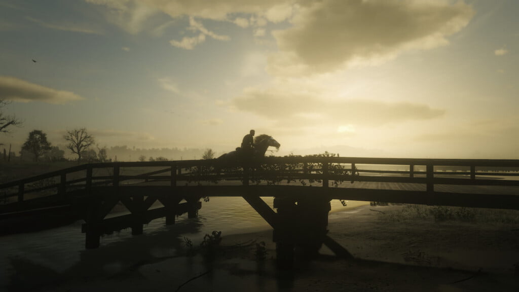Arthur Morgan galloping over a bridge in Bluewater Marsh at dawn.