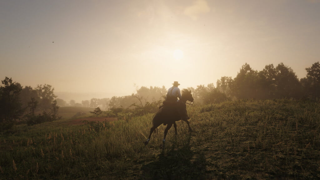 Arthur Morgan cantering through a meadow shortly before sunset.