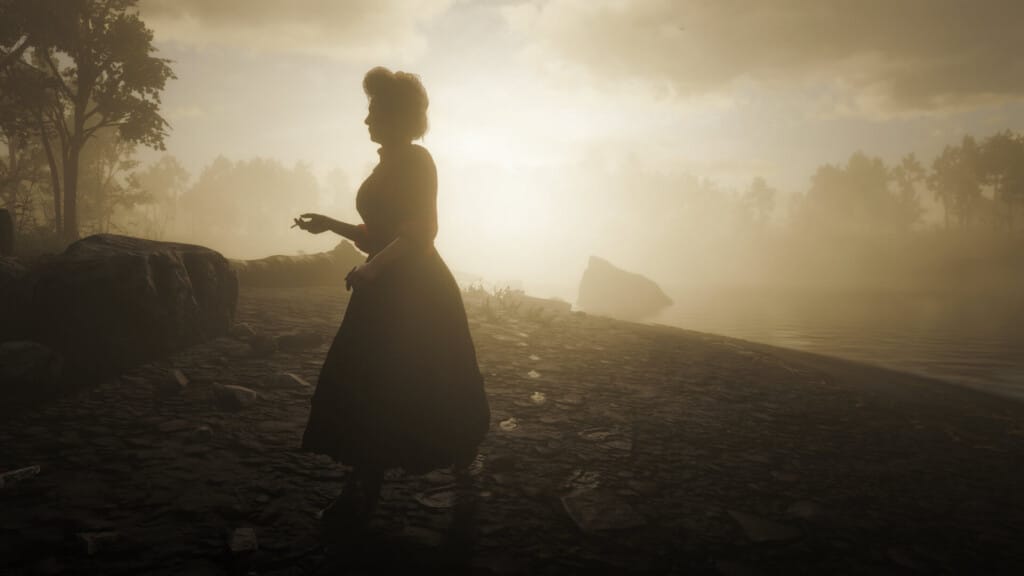 Susan Grimshaw walking on the shore of Flatiron Lake at Clemens Point, smoking a cigarette as the sun rises behind her.