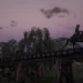 John Marston galloping over a railroad bridge under the rising moon.